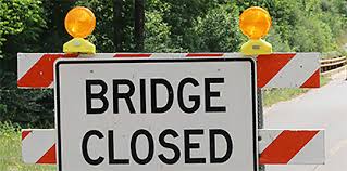 bridge closed sign mounted on red and white stripe barricade with yellow warning lights on top